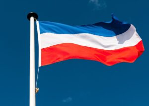 Fahne gestreift vor blauem Himmel in den Farben Schleswig-Holsteins (blau, weiß, rot)