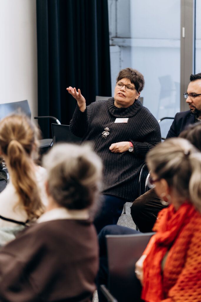 Frau gestikuliert im Stuhlkreis