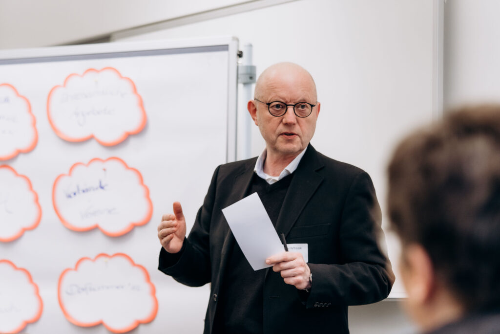 Mann erklärt konzentriert vor Moderationswand