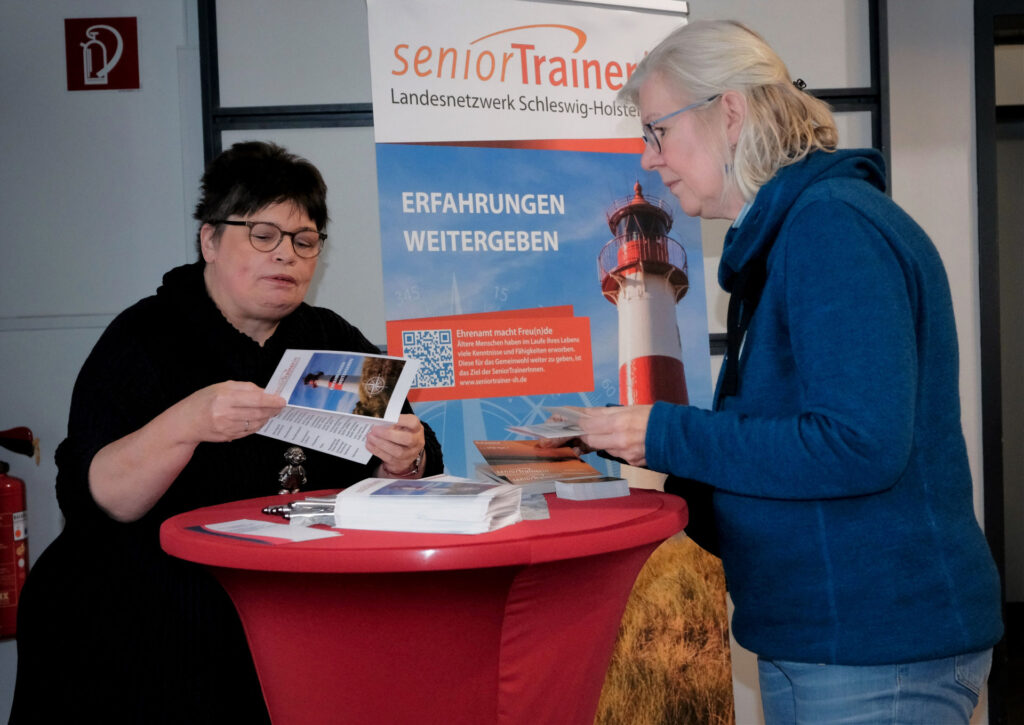 Zwei Frauen studieren Flyer am Stehtisch