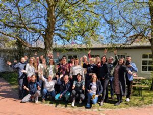 Gruppenbild Menschen unter Baum im Frühling mit blauem Himmel